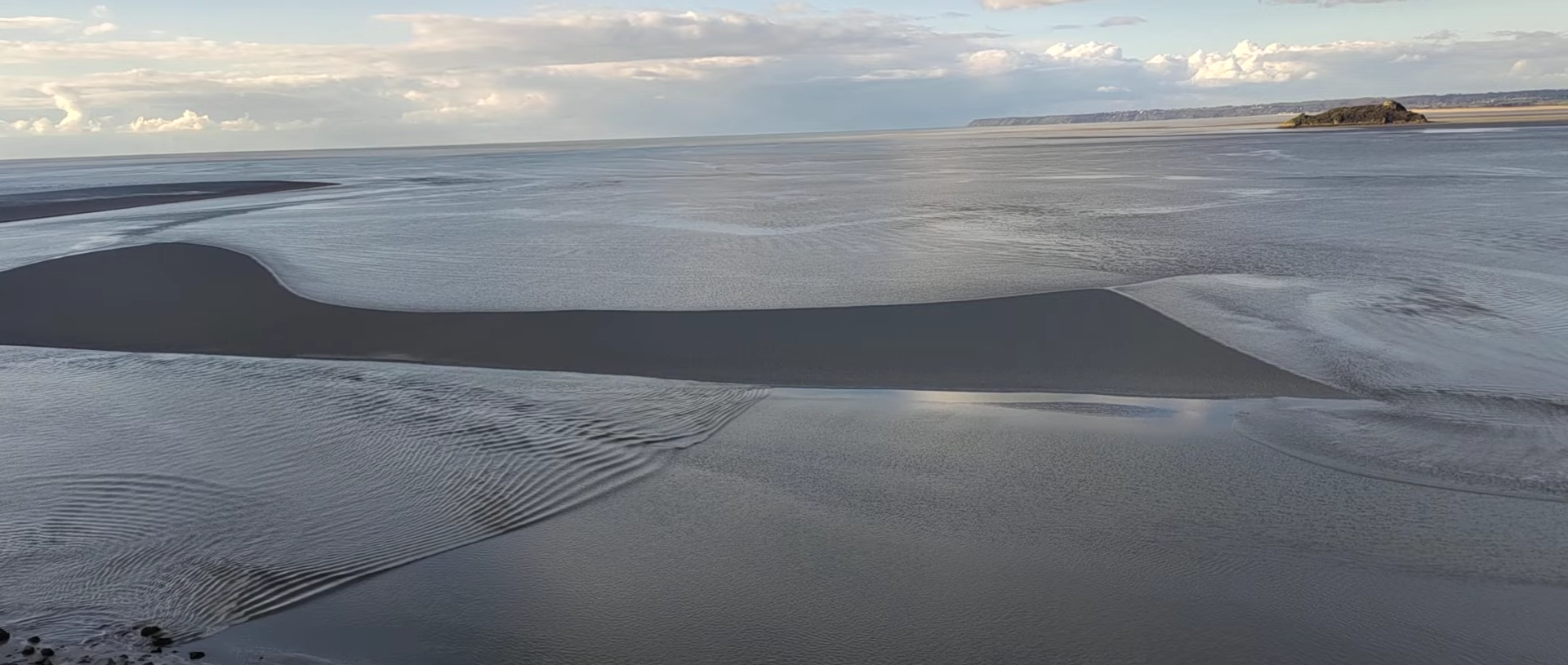 a picture of the rising sea at Mont-Saint-Michel, showing waves of water going towards each other, in two opposite directions